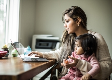 Woman working at home with child on lap